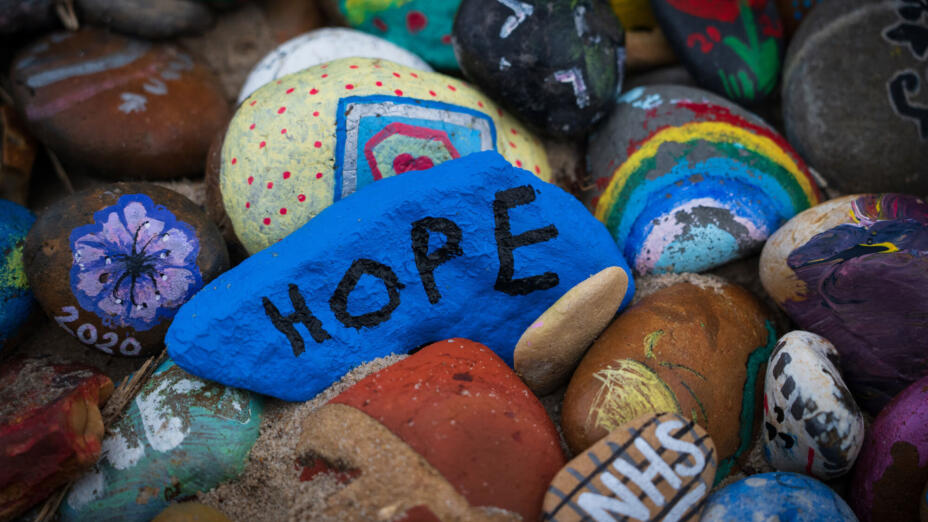 A collection of pebbles one with the word Hope on and one with the NHS logo on