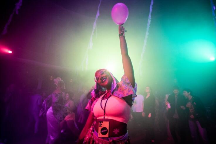 A young woman dances with a balloon at a festival.