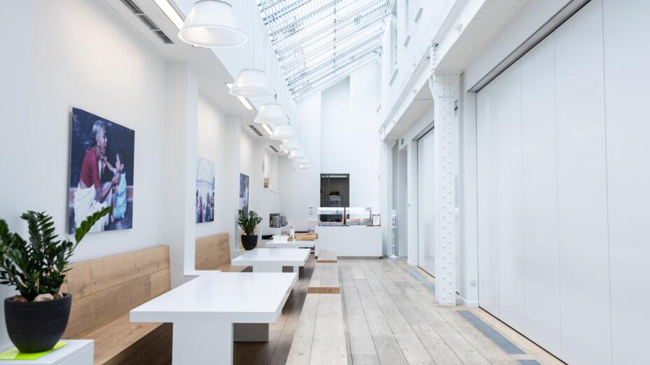 A long atrium in the Paul Hamlyn Foundation offices. The atrium is a high-ceilinged white room, with long bench seating and a sloping glass roof