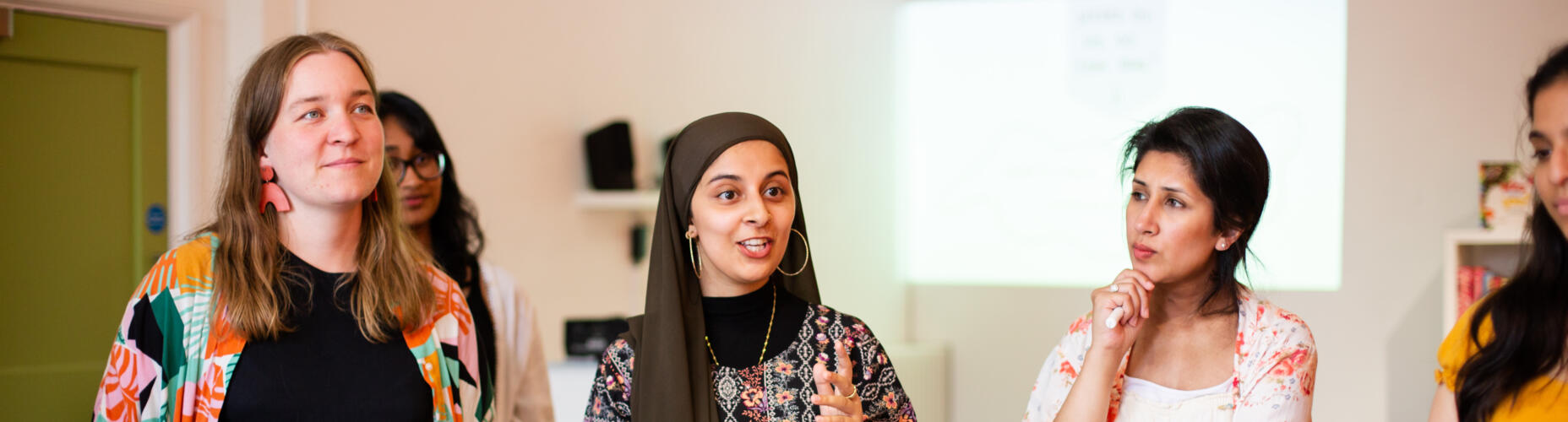 Four young women stand together in conversation. Photo credit: Anisa Fazal