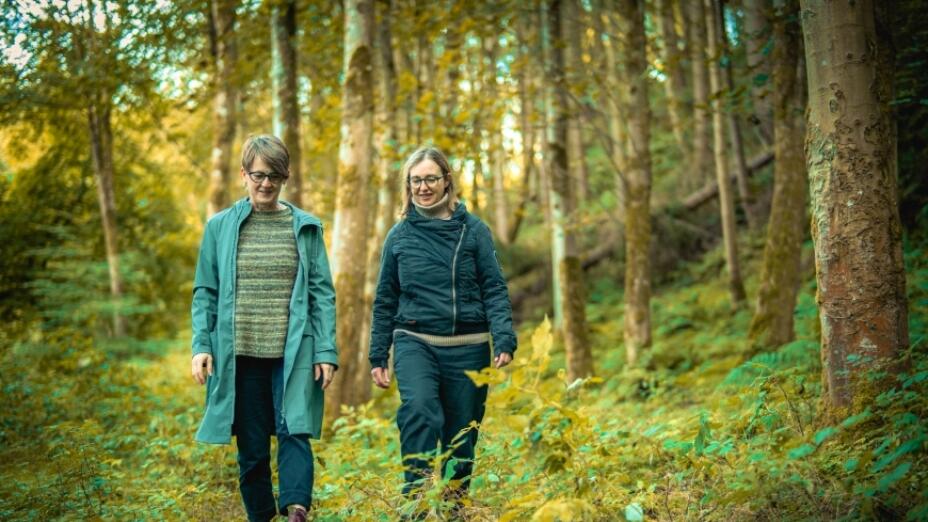 Composers Karine Polwart and Pippa Murphy walk through a sun dappled forest.
