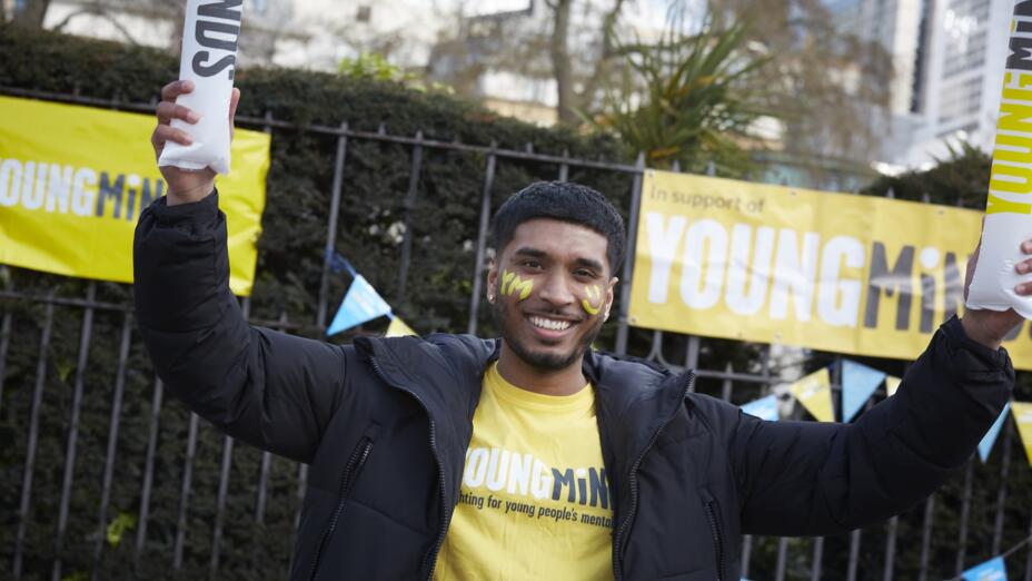 A young man with yellow face paint wearing a yellow YoungMinds t-shirt
