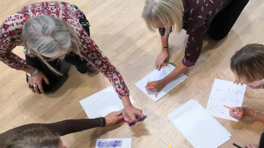 An overhead view of four teachers as they sit on the floor drawing and talking at a Teacher Development Fund cohort learning event.